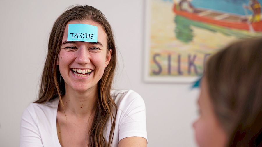Mentor smiler til eleven sin mens de gjør øvelser i tysk privatundervisning.