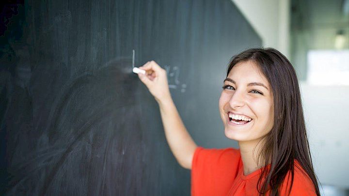 Glad elev viser matematiske beviser på en tavle