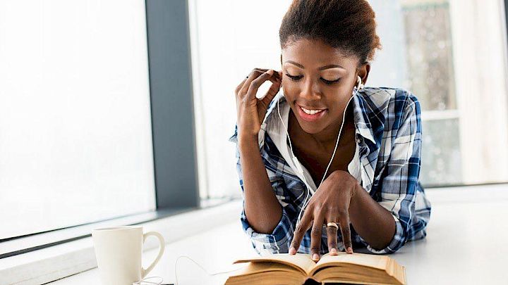 Elev sidder og læser i sin bog mens hun hører musik