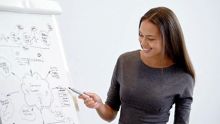 Mentor der skriver på tavle og peger