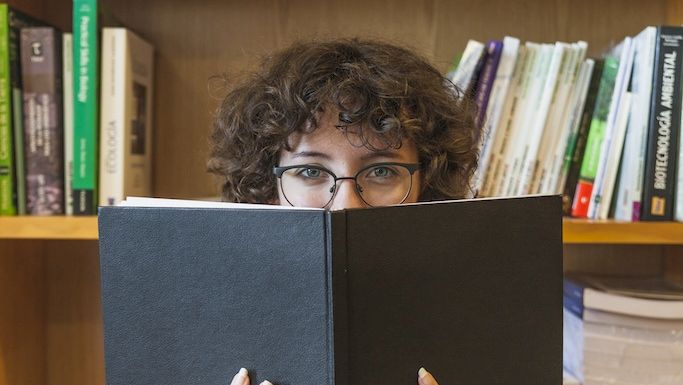 Teenager sidder med hovedet i bogen og læser
