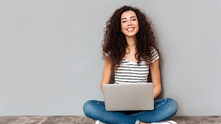 Glad elev sidder og forbereder opgaver på computer