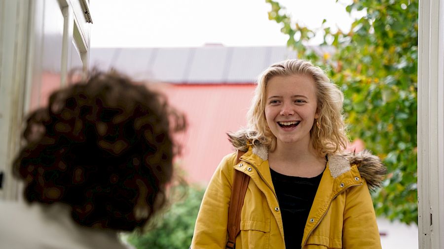 Mentor smiler til eleven sin mens hun blir sluppet inn før undervisningen.