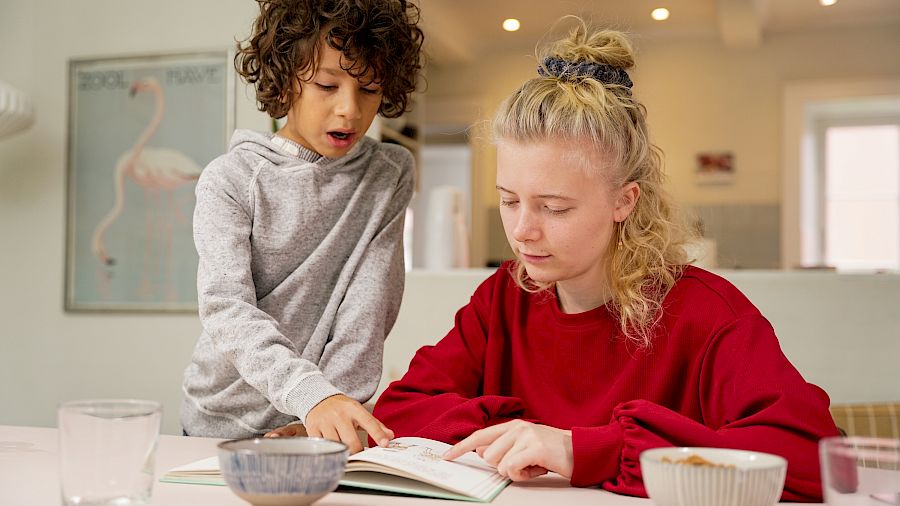 Elev smiler mens han løser oppgaver sammen med mentoren sin.