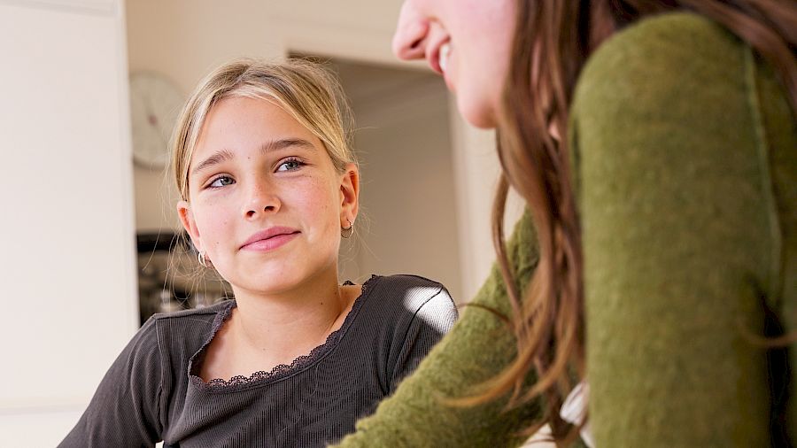 Elev sitter glad i undervisningen og smiler til mentoren sin.