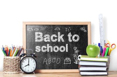 Tavle hvor det står "Back to school" omkranset av klokke, bøker, blyanter og et eple