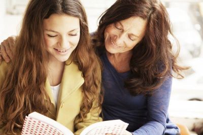 Glad mor og datter som sitter og ser i en bok sammen