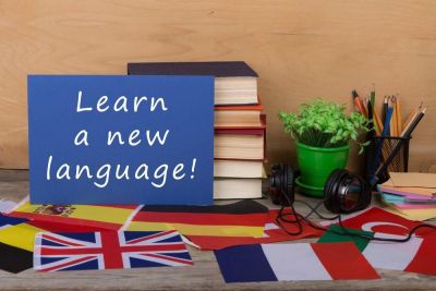 Flagg og bøker rundt et skilt hvor det står "Learn a new language"