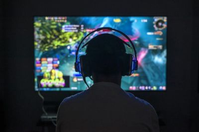 En person spiller videospill i et mørkt rom med høretelefoner