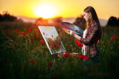 Jente står i en vakker eng og maler mens solen går ned
