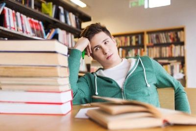 Umotivert skoleelev ser frustrert over på en stakk bøker